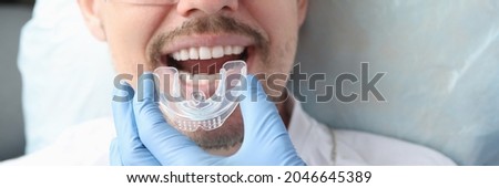Dentist trying on mouthguard for man patient Royalty-Free Stock Photo #2046645389