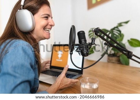 Mature woman recording a podcast using microphone and laptop from her home studio