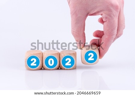 A hand putting wooden number 2 in the year 2022 isolated on white background