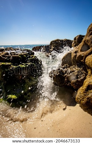 A vertical shot of rocks on the beach under a blue clear sky