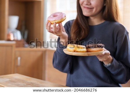 A young woman holding and enjoyed eating donuts at home