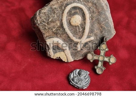Enamelled tile from church with a stylized fish image. Small crucifix with enamels. Lead seal with a picture of the holy. Subjects associated with Christianity.