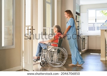 Caregiver or nurse pushes a paralyzed elderly woman in a wheelchair in a retirement home Royalty-Free Stock Photo #2046706850