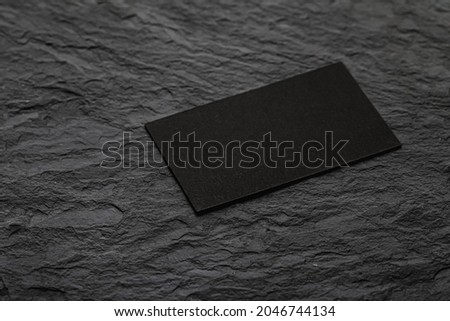 Blank black business card on stone surface.