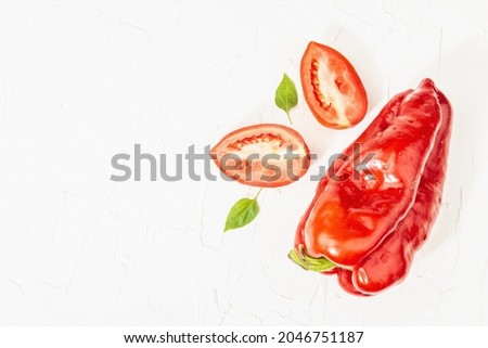 Giant red bell peppers and tomatoes on white background. Sweet vegetable, new harvest, fresh ingredient for healthy food, top view