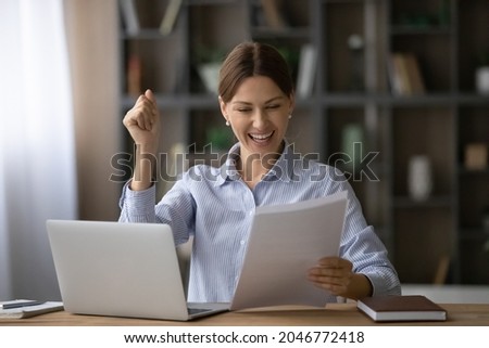 Overjoyed woman reading good news in letter, rejoicing success, job promotion, sitting at work desk with laptop, excited businesswoman working with correspondence, happy student received scholarship Royalty-Free Stock Photo #2046772418