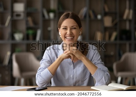 Head shot portrait of smiling woman in earphones looking at camera, successful businesswoman involved in online conference or negotiations, making video call, mentor coach leading internet lesson Royalty-Free Stock Photo #2046772556