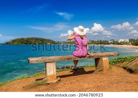 Woman seatted on a bench at Mirissa tropical Beach in a sunny day in Sri Lanka