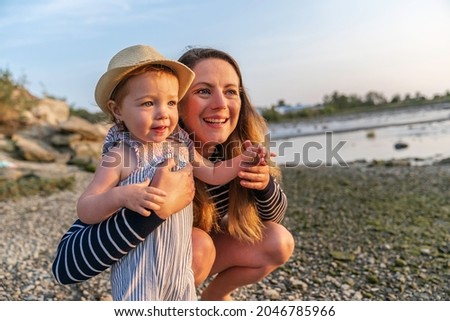 A Mother have fun with baby on the beach at the sunset