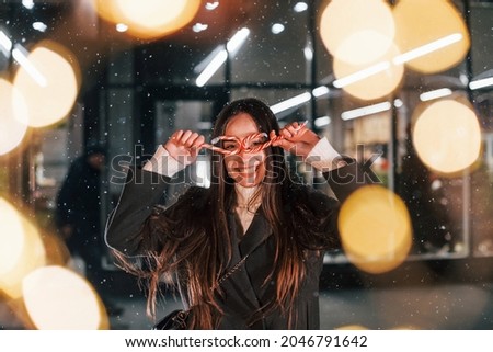 With candies in hands. Cheerful woman is outdoors at Christmas holidays time. Conception of new year.