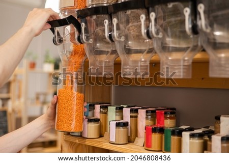 A man fills a jar with red lentils. Selling bulk goods by weight in an eco store. Trade concept without plastic packaging Royalty-Free Stock Photo #2046808436