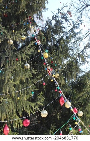 the branches of the Christmas tree are decorated with toys in the city park in winter