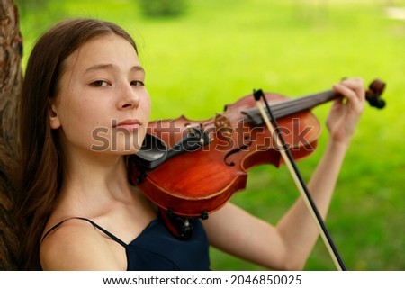 Asian girl in nature with violin. High quality photo