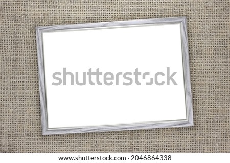 Wooden frame with white background inside on brown burlap background with beautiful brown fabric canvas texture as vintage burlap background with burlap texture and beautiful burlap color