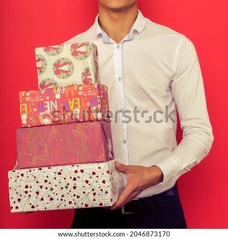 Handsome asian businessman holding gift box over red background - image