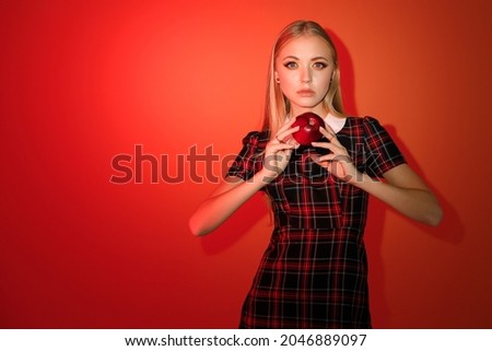 stylish model in a modern autumn image with bright autumn makeup and a red apple on a fashion background