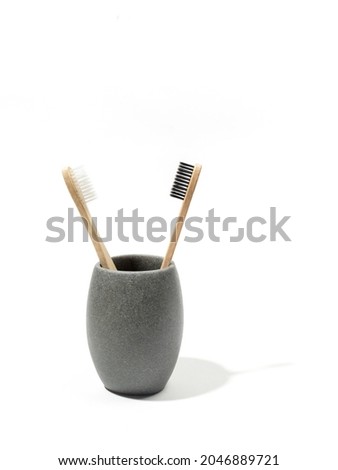 Two eco-friendly wooden bamboo toothbrushes in grey stone cup on white background. Copy space.