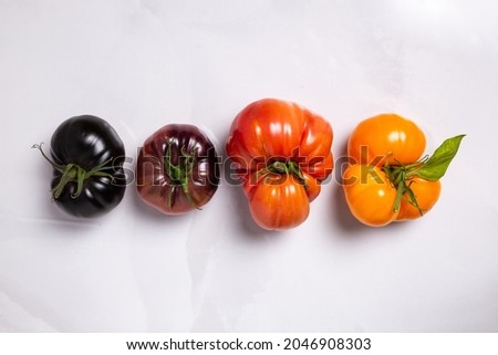 A variety of colorful heirloom tomatoes on white marble Royalty-Free Stock Photo #2046908303