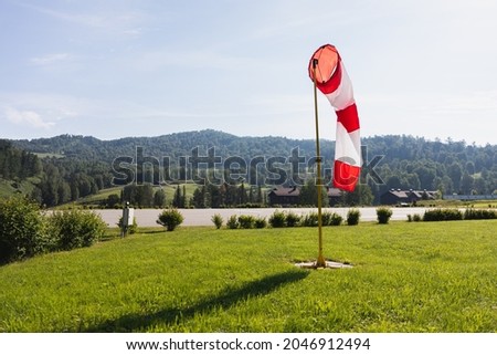 A red and white windsock next to the helipad. A beautiful landscape without people. Mountains on a bright day. Royalty-Free Stock Photo #2046912494