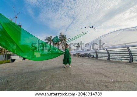 A girl carrying the Saudi flag on the Saudi National Day and the air show Royalty-Free Stock Photo #2046914789
