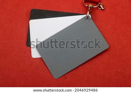 Grey card with a red strap on red background, a photographer’s tool, determining the correct white balance