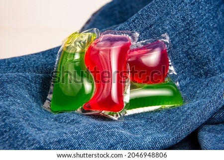 Red green capsule for cloth washing liquid powder on cotton denim background