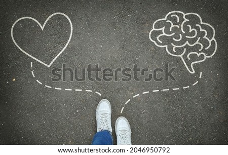 Heart or brain. Legs in white sneakers in front of white heart and brain symbols on the gray asphalt background. Path choice concept
 Royalty-Free Stock Photo #2046950792