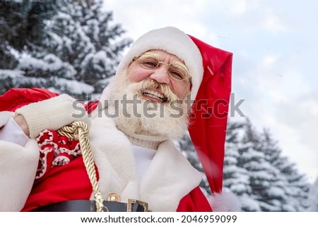 Xmas Santa Claus with real beard in the northern forest in winter among snow-covered firs and pines outside the city in the wild. Festive image for advertising design of banners, cards or calendars