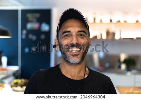 Handsome Coffee Shop Owner Working in a Cozy Loft-Style Cafe. Successful Restaurant Manager Standing Happy Behind Counter and Smiles on Camera. Royalty-Free Stock Photo #2046964304