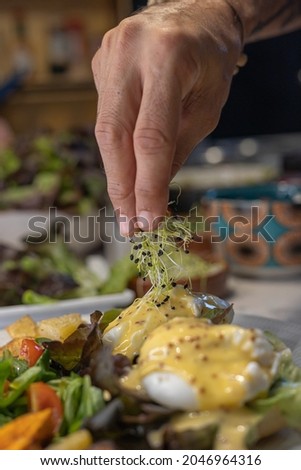 Chef cook preparing benedict eggs in his kitchen. Eggs Benedict on toasted muffins with smoked salmon and sauce Royalty-Free Stock Photo #2046964316