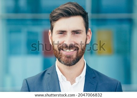 Portrait of young handsome man with beard, businessman looking at camera and smiling close up photo