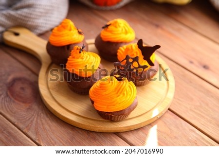 Halloween chocolate cupcakes with decor on wooden background