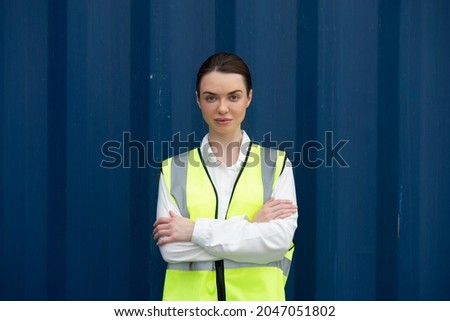 A portrait of an Asian woman working in a safety gear working in a port warehouse.