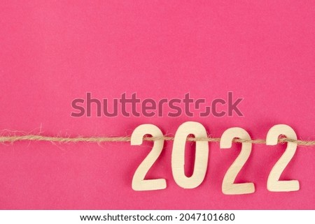 Wooden number 2022 and rope on pink background with copy space for your text or message.