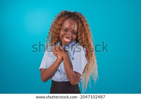 black woman with curly hair in studio photo wearing blue shirt and black skirt and making various facial expressions.