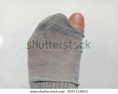 a photo of Broken left side sock with a hole in a thumb with white background Royalty-Free Stock Photo #2047116851