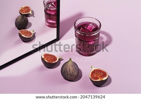 Colorful cocktail garnished with figs. Cocktail purple color garnished with figs, frontal view. On a pink background Royalty-Free Stock Photo #2047139624