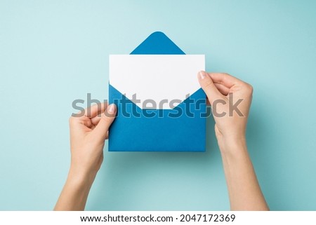 First person top view photo of female hands holding open blue envelope with white paper sheet on isolated pastel blue background with empty space