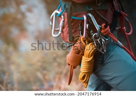 Climbing equipment, ropes, carabiners, harness, belay, close-up of a rock-climber put on by a girl, the traveler leads an active lifestyle and is engaged in mountaineering. Royalty-Free Stock Photo #2047176914