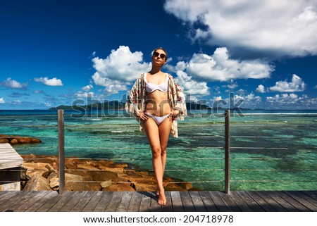 Woman on a tropical beach jetty at at Seychelles, La Digue.