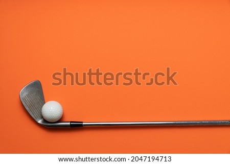 golf ball and golf club on orange background, sport concept