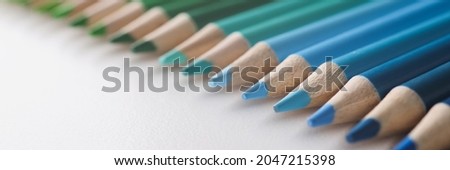 Many multi-colored pencils lying in colors of rainbow on white background