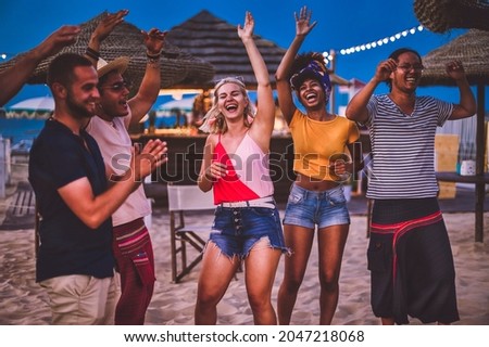 Group of happy multiracial friends dancing at sunset beach party in summer vacation - Young millennials people having fun at weekend in the outdoor  club - Youth lifestyle and nightlife concept Royalty-Free Stock Photo #2047218068