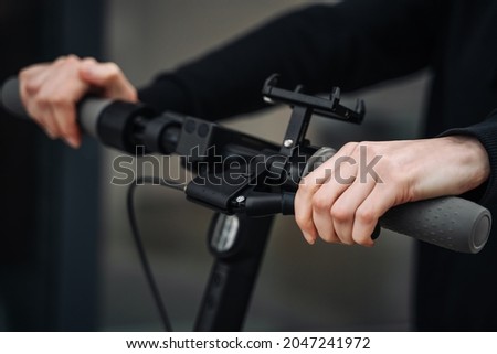 Women's hands hold the steering wheel of the electric scooter, pressing the brake. Royalty-Free Stock Photo #2047241972