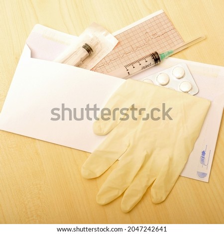Syringes pills in a white envelope have surgical glove and ECG result