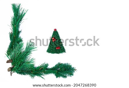 Christmas tree made of spruce needles, decorated with red rowan berries framed by pine branches on white background. Christmas, New Year minimalistic concept. Copy space. Flat lay.