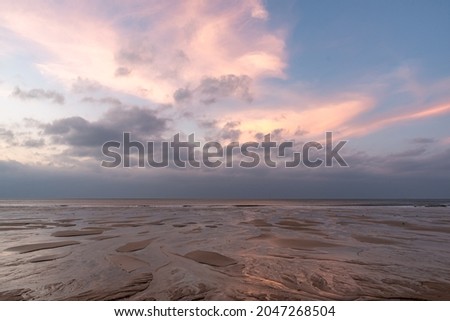 In the early morning by the sea, the sky and the beach are slightly red Royalty-Free Stock Photo #2047268504