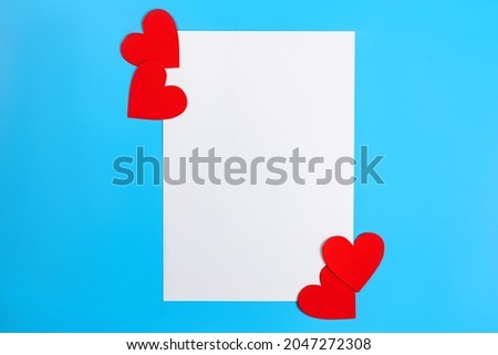 white sheet of paper and bright red hearts on blue background