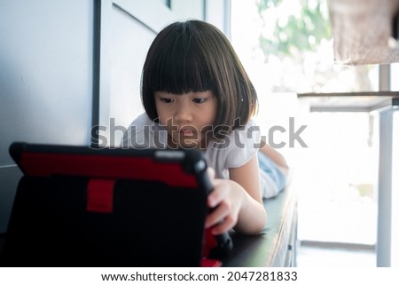 chinese child addicted tablet, asian girl playing smartphone, kid watching cartoon