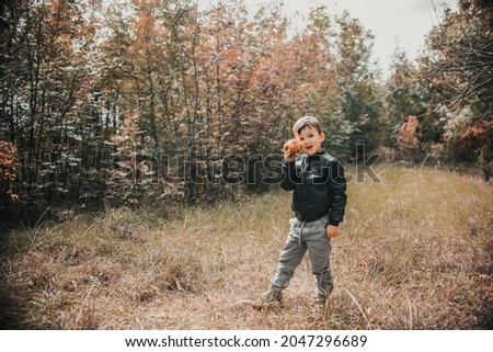 A cheerful boy in the autumn forest with an apple in his hands Royalty-Free Stock Photo #2047296689